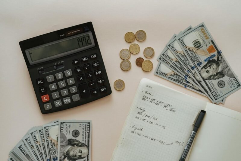 how to budget and save money with pictures of cash and coins with calculator, pad and pen to count money.
