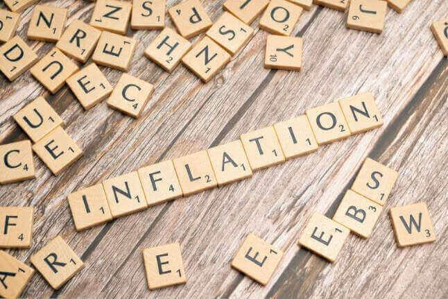 Scrabble tiles spelling “INFLATION” on a wooden surface, illustrating what inflation means and its effects.