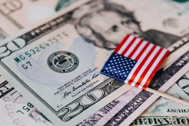 illustration of US dollar bills with a small American flag, symbolizing the weaker US dollar